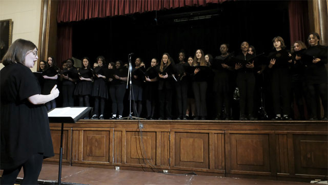 A person standing in front of a group of people in black robesDescription automatically generated with low confidence